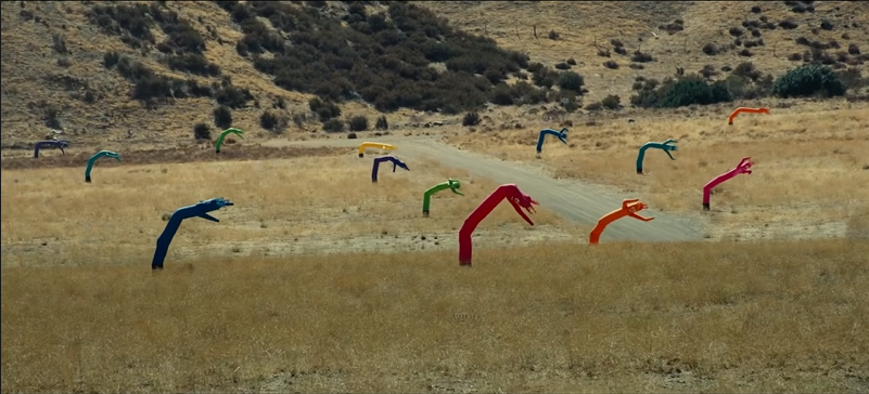 Wind Dancers across a dry, yellow California ranch all bend to the right of the screen in the wind.