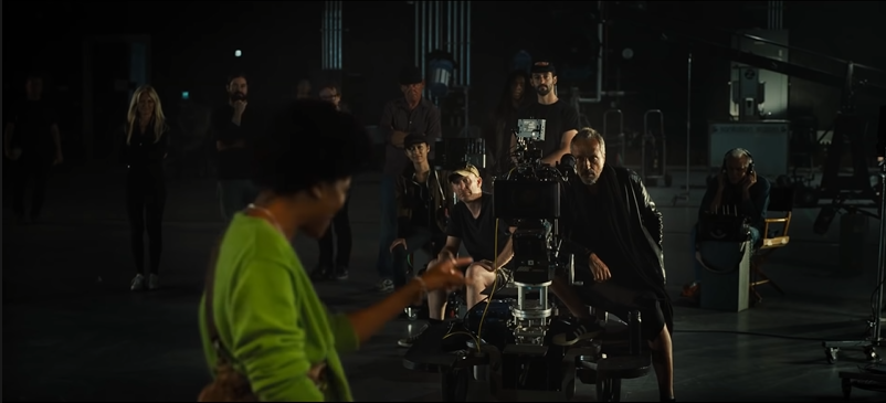 Keke’s character points into the film crew's camera.  The lens is a prominent black void.